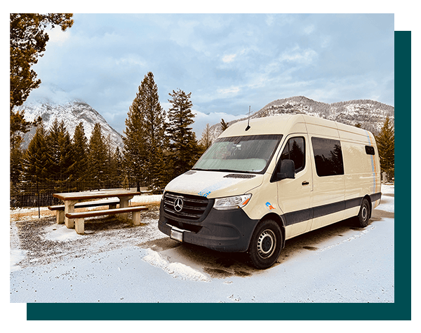 Our DIY Sprinter campervan parked in Banff National Park during winter with snow-covered mountains in the background